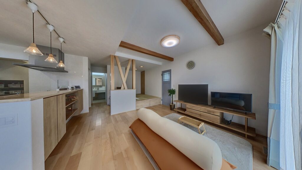 折り上げ天井と化粧梁が印象的なLDK。対面キッチン、小上がり畳スペース、木目の床が広がる明るい空間。